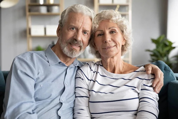 Affectionate mature retired married couple cuddling on comfortable sofa. — Stock Photo, Image