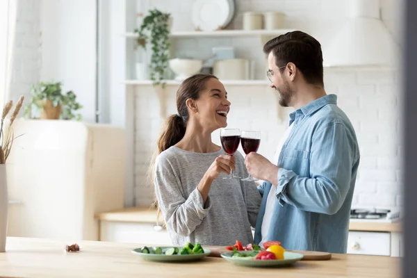 Överlycklig ung par klamrar glas koka tillsammans i köket — Stockfoto