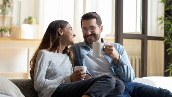 Glückliches junges Paar entspannt sich auf gemütlicher Couch und trinkt Tee — Stockfoto