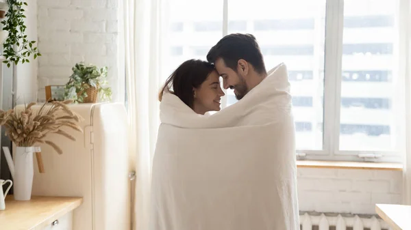 Loving couple wrapped in cover having romantic moment at home — Stock Photo, Image