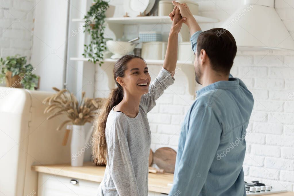 Happy young couple dancing in modern kitchen at home