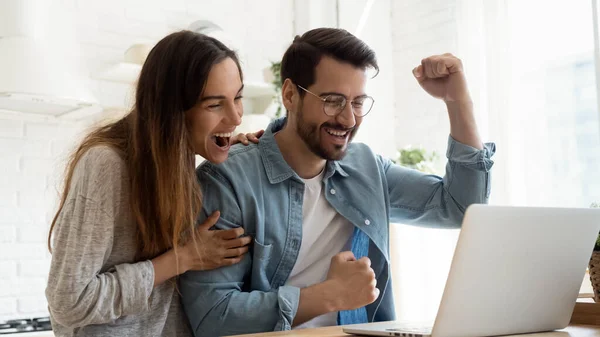 Spännande par känner euforisk läsning goda nyheter på laptop på nätet — Stockfoto
