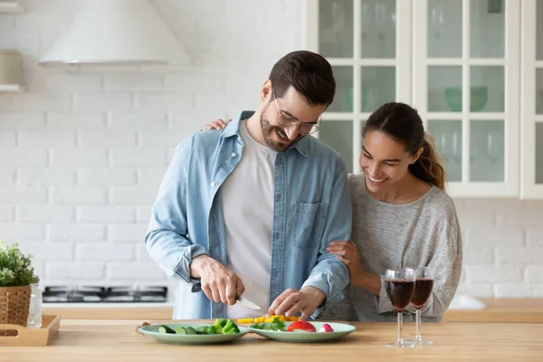 Glad tusenårig par matlagning mat i köket tillsammans — Stockfoto