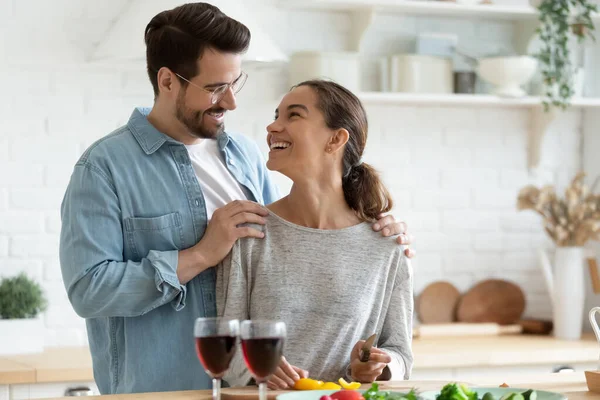 Happy millennial couple tenants cook food in modern kitchen