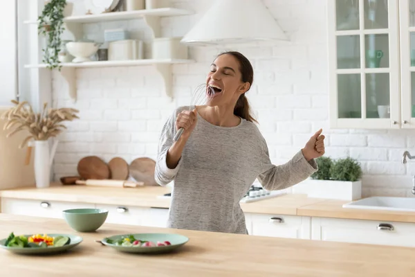 Happy young woman have fun singing cooking at home — Stock Photo, Image