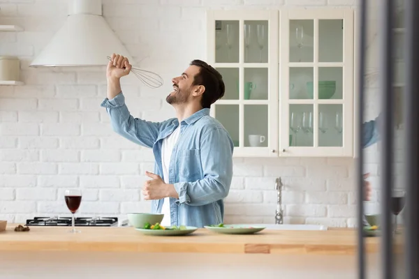 Überglücklicher junger Mann hat Spaß beim Kochen in Küche — Stockfoto