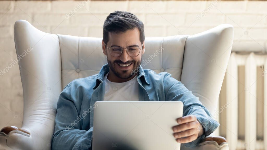Happy young man relax in chair using laptop