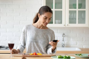 Milenyum kızı cep telefonundan yemek tarifi kullanıyor.