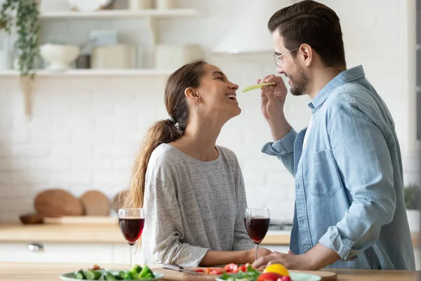 Happy millennial couple have fun celebrating anniversary at home kitchen