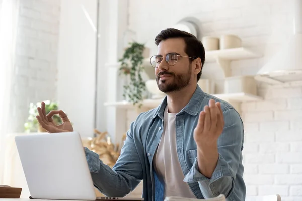 Hombre joven tranquilo meditar en el lugar de trabajo en casa — Foto de Stock