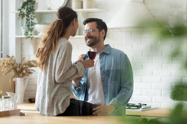 Mutlu genç çift ev mutfağında şarap içerek sarılıyor. — Stok fotoğraf
