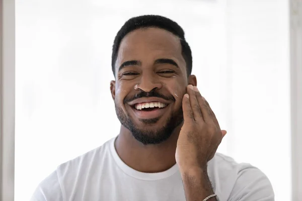 Potret pria birasial tersenyum menggunakan krim wajah — Stok Foto