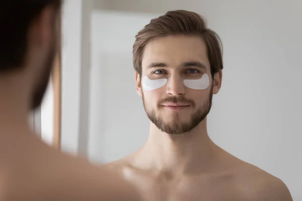 Jovem aplique adesivos de hidrogel para uma aparência fresca no banho — Fotografia de Stock