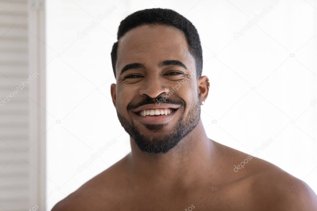 Headshot portrait of smiling biracial man posing in bathroom