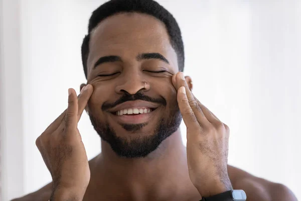 Smiling african american man massage face in bathroom — Stock Photo, Image