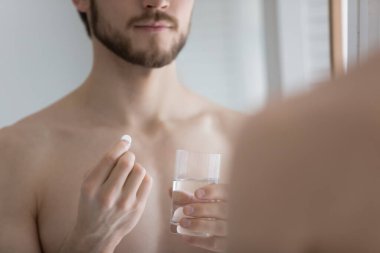 Genç adam banyoda ilaç alıyor.