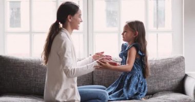 Gülümseyen genç melez anne kızıyla el oyunu oynuyor..