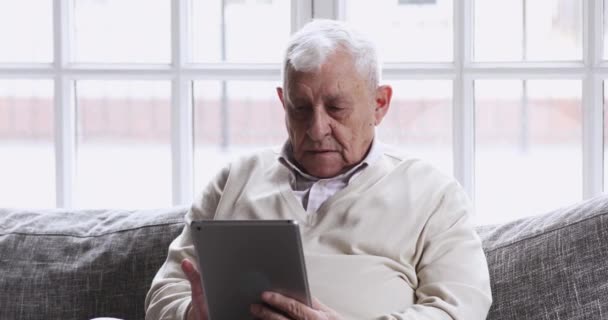 Konzentrierter Großvater mittleren Alters surft Gesundheitsinformationen auf Tablet. — Stockvideo