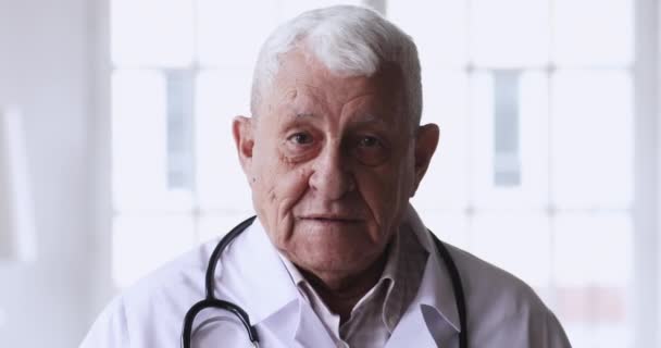 Hlava záběr s úsměvem 80s starší hlava lékař při pohledu na kameru. — Stock video