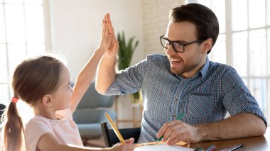 Çok mutlu baba ve küçük kız evde başarıyı kutluyor.