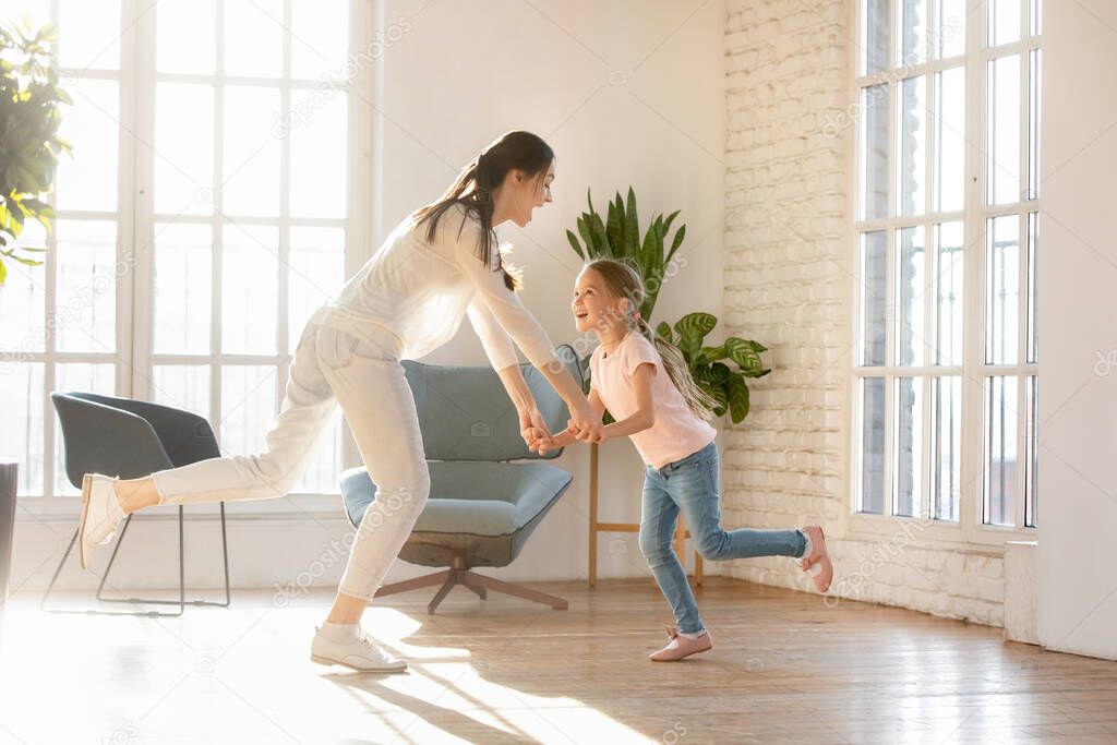 Overjoyed young mom have fun dancing with daughter