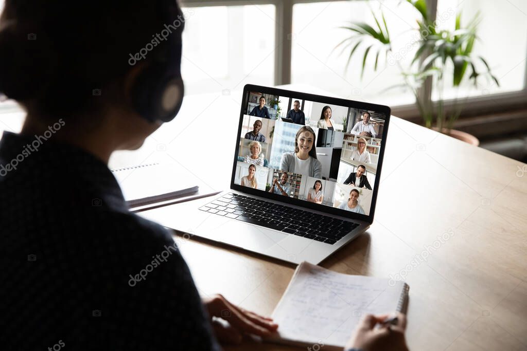 Back view of woman worker engaged in online team meeting