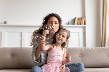 Mutlu anne ve tatlı küçük kız sabun köpüğü üflüyor.