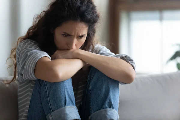 Close up depressed young woman sitting alone, thinking about problems