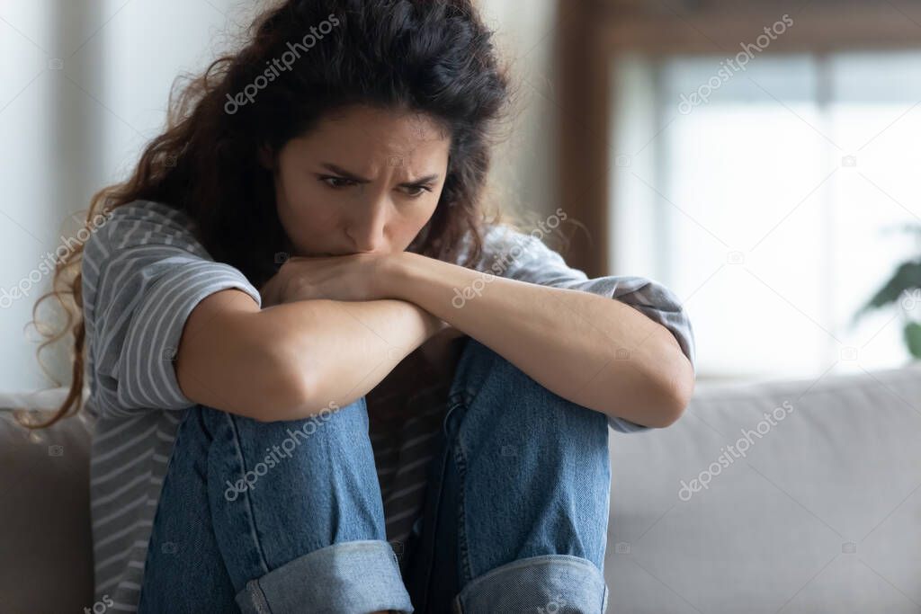 Close up depressed young woman sitting alone, thinking about problems