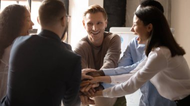 Heyecanlı çeşitli iş adamları şirket toplantısında el ele tutuşuyor.