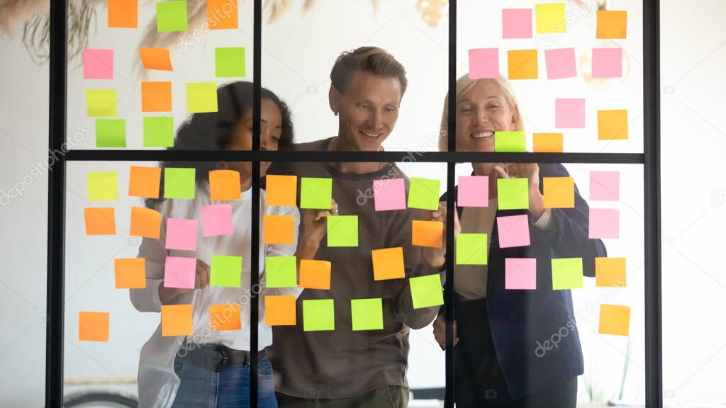 Diverse employees team writing tasks on colorful sticky papers