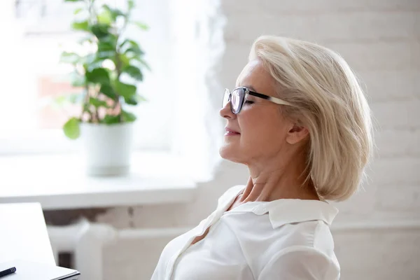 Middle-aged female employee relax take nap at workplace