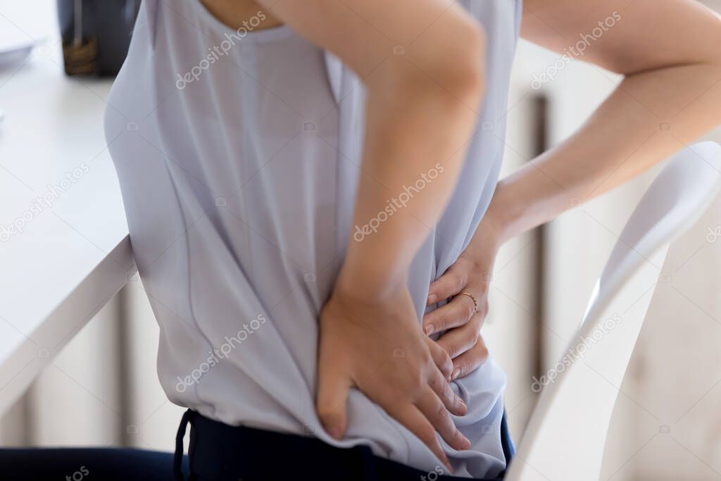 Close up of female employee suffer from lower back ache