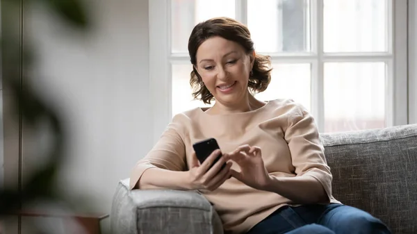 Lächeln reife Frau SMS auf Smartphone zu Hause — Stockfoto