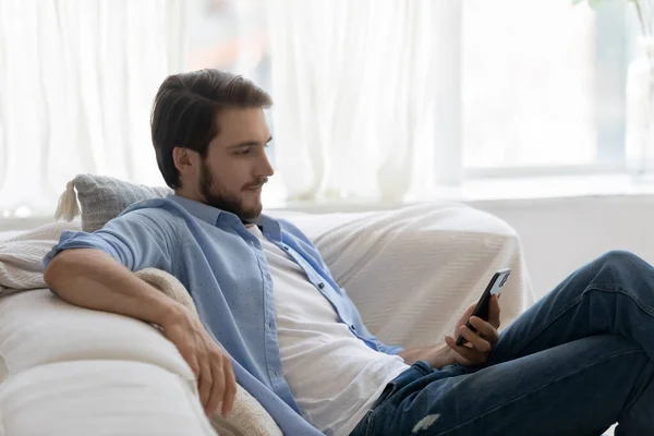 Caucasian man relax on sofa using smartphone