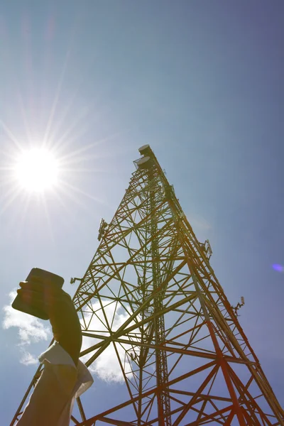 Mulher com smartphone perto da torre de telecomunicações — Fotografia de Stock