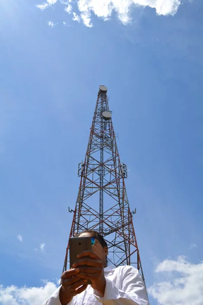 Mulher com smartphone perto da torre de telecomunicações — Fotografia de Stock