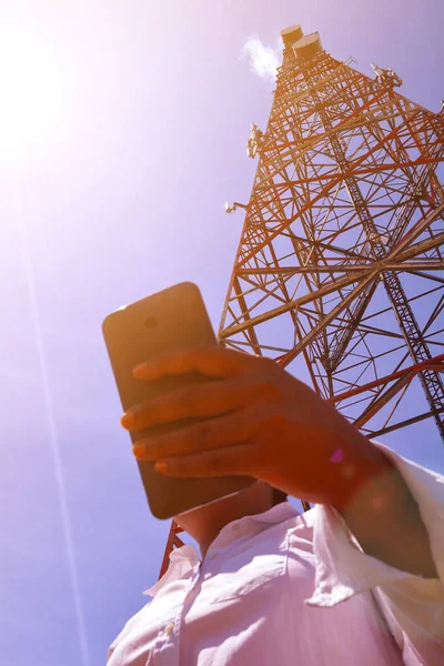 Žena s smartphone poblíž telekomunikační věž — Stock fotografie