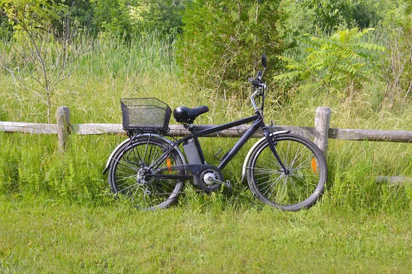 Rower elektryczny na ogrodzenie drewniane — Zdjęcie stockowe