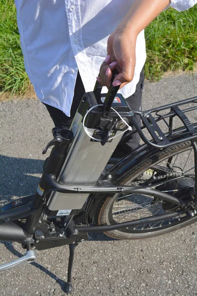 Women holding battery pack of electric bicycle near her e bike.