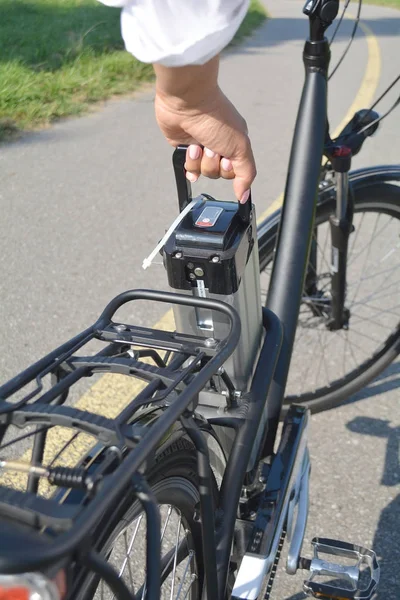 Women holding battery pack of electric bicycle near her e bike.