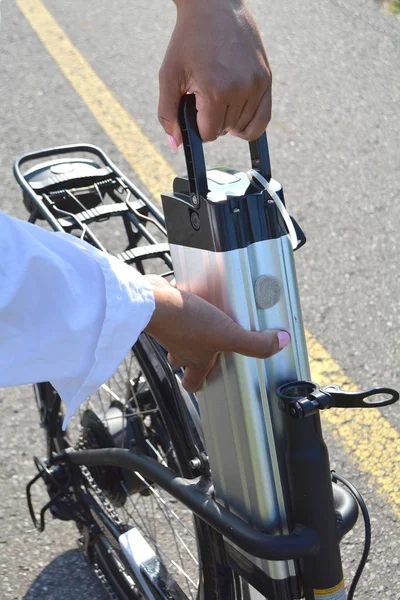 Women holding battery pack of electric bicycle near her e bike.