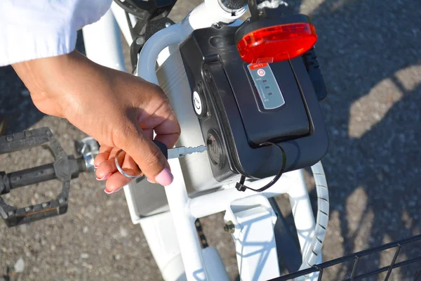 Las mujeres ciclistas sostienen la llave de la batería de la bicicleta eléctrica . — Foto de Stock