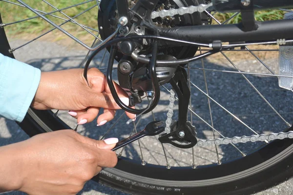 Jonge vrouw met roze nagels is de vaststelling van haar elektrische fiets — Stockfoto