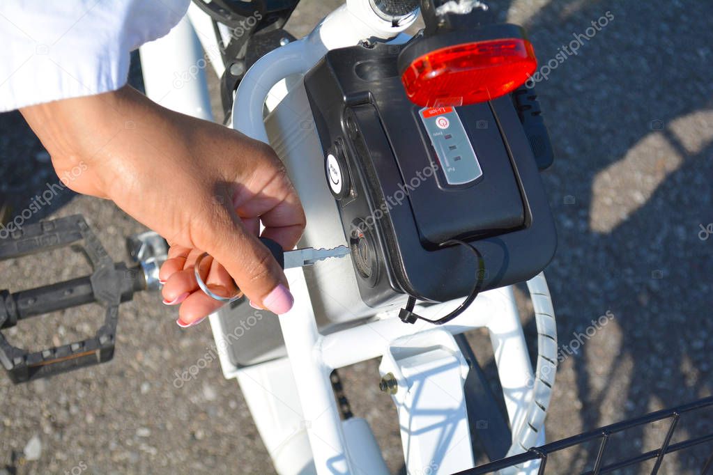 Women cyclist hold the key of the electric bicycle battery pack.