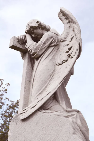 Outdoor weathered statue of angel on cross