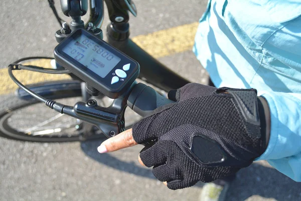 Ręka kobiety z jasne różowe paznokcie na rower elektryczny — Zdjęcie stockowe