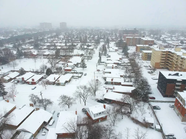 High level of snow storm, winter weather forecast alert day in the city. Top aerial view of people houses covered in snow, bird eye view suburb urban housing development. Quite neighbourhood, Canada.