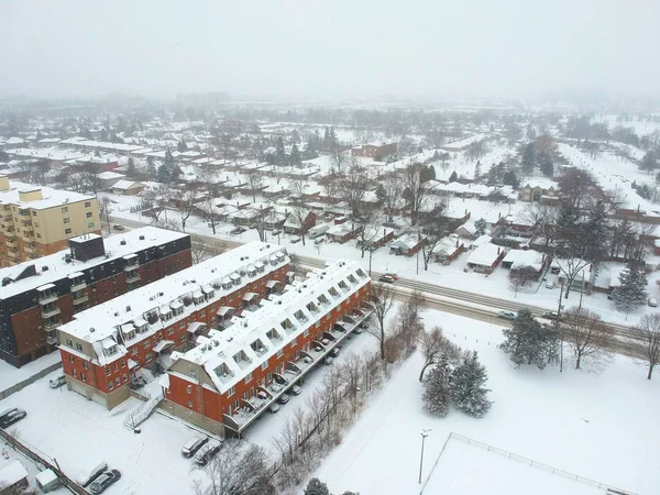 High level of snow storm, winter weather forecast alert day in the city. Top aerial view of people houses covered in snow, bird eye view suburb urban housing development. Quite neighbourhood, Canada.