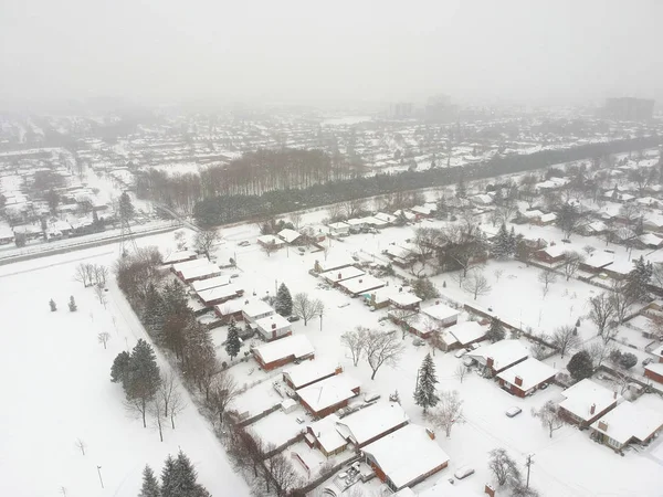 High level of snow storm, winter weather forecast alert day in the city. Top aerial view of people houses covered in snow, bird eye view suburb urban housing development. Quite neighbourhood, Canada.